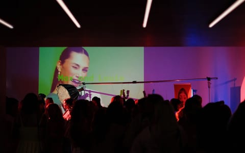 Event space with coloured projection lighting, screen, crowd, and microphone stand