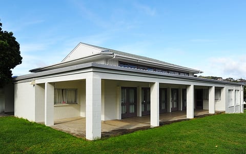 Single-storey rendered-block hall with covered verandah and lawn