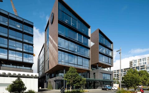 Multi-storey commercial building with timber and glass facade under blue sky