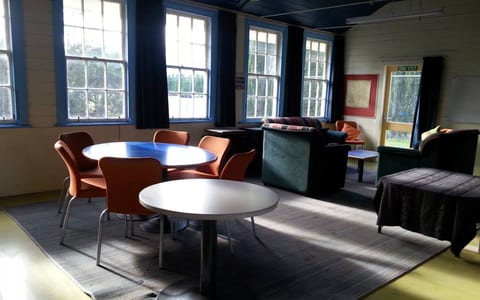 Casual lounge room with round tables, mixed chairs and bright windows with blue trim