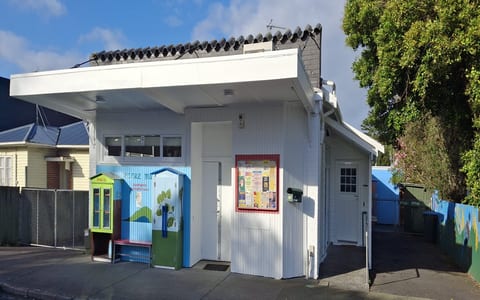 Small white weatherboard community building with covered entrance and notice board