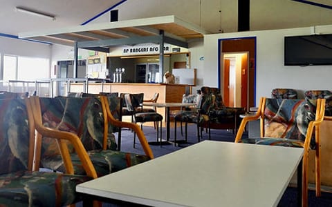 Clubroom interior with tables, chairs and bar counter visible in background