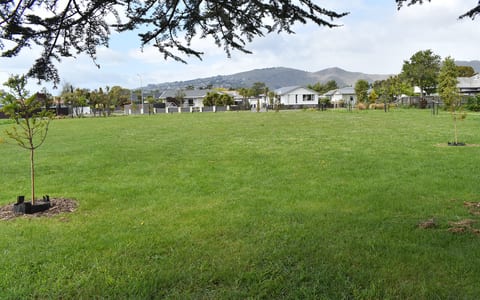 Open suburban park with lawn, young trees and hills in the background