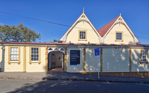Cream weatherboard heritage hall with decorative gable trim, red roof and arched vehicle entrance