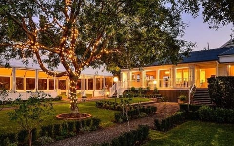 Estate homestead at dusk with fairy-lit trees and illuminated marquee