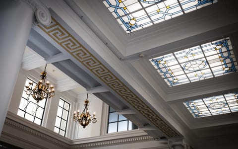 Grand hall interior with ornate stained-glass skylights, moulded cornices, and chandeliers