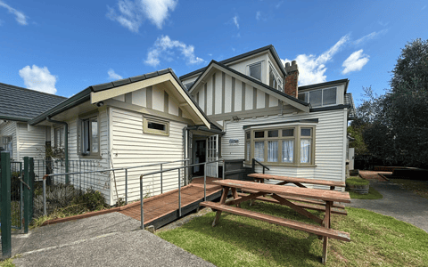 White timber community house exterior with deck and picnic tables on lawn