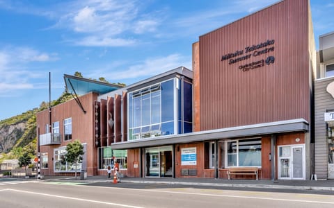 Modern timber-clad community centre building on a town street with hill backdrop