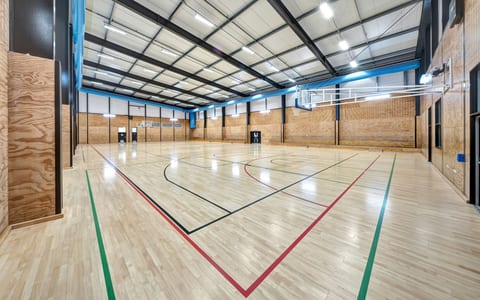 Large indoor sports court with timber floor and blue steel roof structure