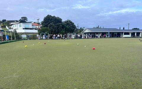Bowling green with coloured bowls and clubhouse building in background