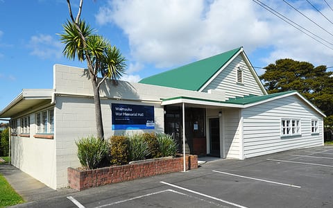 Waimauku War Memorial Hall exterior with green metal roof and small car park