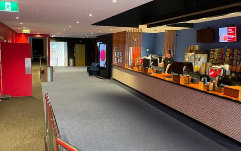 Cinema foyer with ticket counter, red walls, and carpet