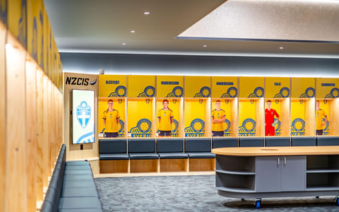 Sports changing room with lockers, player photos and a central briefing table