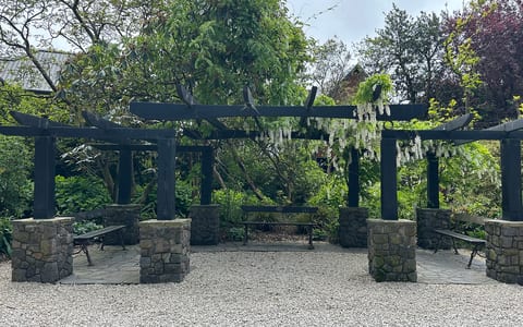 Pergola with stone pillars and hanging flowers in a garden reserve