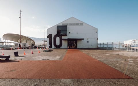 Large white gabled shed building with bold number 10 on facade, waterfront setting