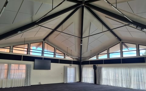 Large octagonal hall with high vaulted ceiling, exposed beams and sheer curtains