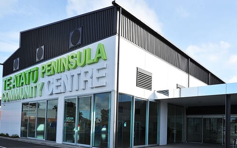 White and dark two-storey building with green signage and large glazed ground-floor shopfront