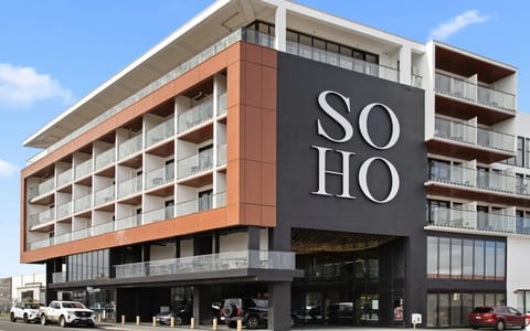 Multi-storey building exterior with terracotta cladding, balconies, and large branded signage, street level