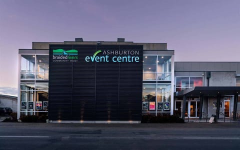 Modern event centre exterior at dusk with illuminated signage on dark cladded facade