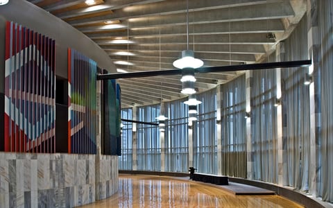 Curved hall with timber floor, marble-clad wall, hanging pendant lights and sheer curtained windows