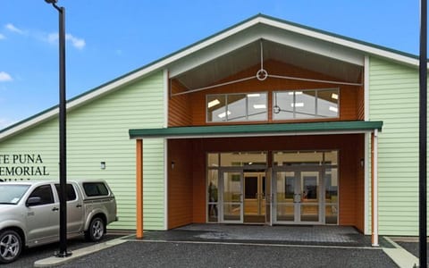 Light green clad hall exterior with signage and carpark