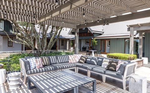 Covered outdoor terrace with timber pergola, grey outdoor sofas and courtyard building surrounds