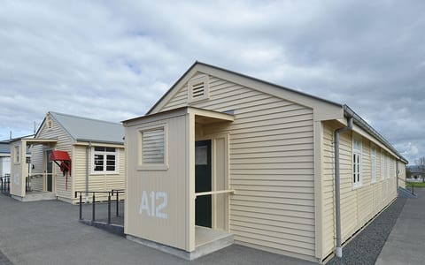 Single-storey cream weatherboard barrack buildings with 'A12' numbering