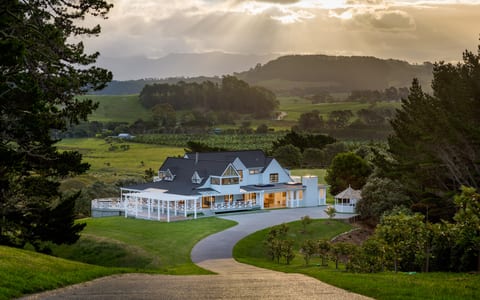 Main building lit at dusk seen from the hilltop driveway with valley and hills behind