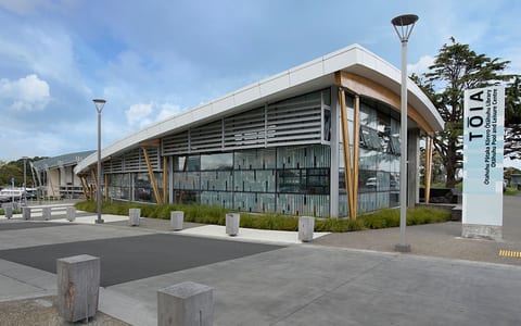 Contemporary low-rise building with angled roof, timber columns, louvre cladding and signage