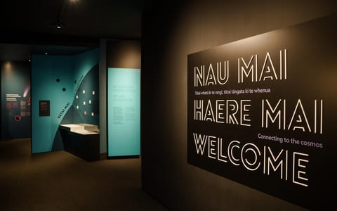 Dark museum entrance corridor with welcome signage and exhibition panels
