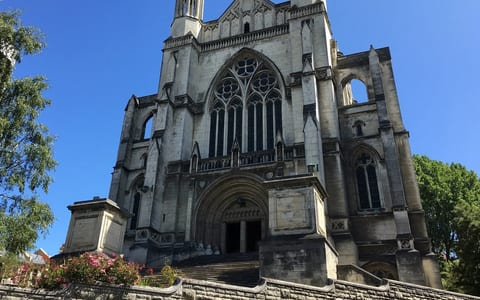 Large Gothic stone cathedral exterior with twin spires, rose window, grand entrance steps