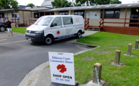 Community house building with van parked outside and A-frame sign on footpath