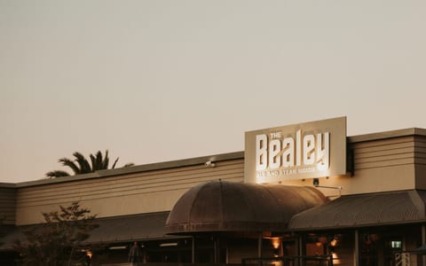 The Bealey signage lit up on a low-rise commercial building at dusk