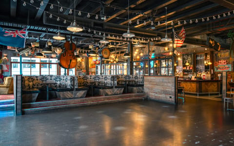Eclectic bar interior with exposed trusses, patterned booths, large cello hanging from ceiling and music memorabilia