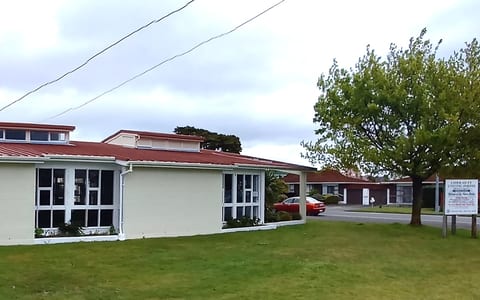 White rendered hall with stepped parapet and red-tiled roof wing, grassed surrounds
