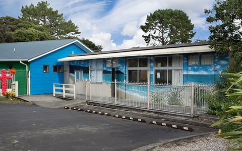 Single-storey blue-painted community hall exterior with fenced entrance