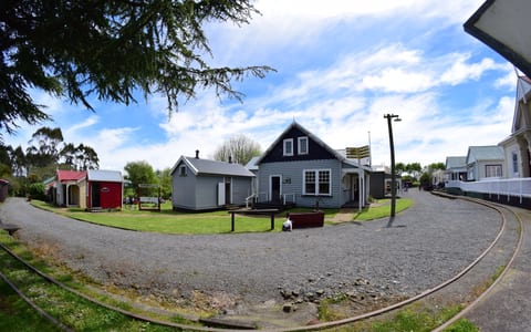 Open-air heritage village with weatherboard cottages, curved rail track, and gravel paths