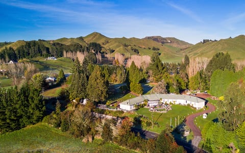 Aerial view of lodge buildings set among trees in a rural valley with hills