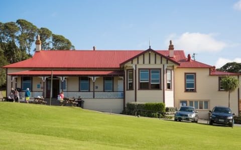 Heritage lodge building with red roof and verandah on a grassed site