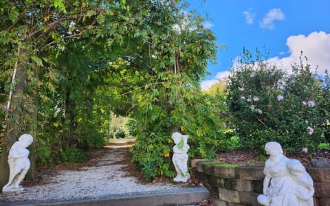 Garden path lined with classical stone statues leading through lush subtropical plantings