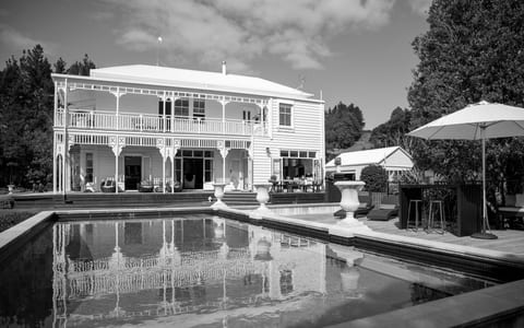 Two-storey white weatherboard villa with wraparound verandahs, a pool terrace and outdoor bar