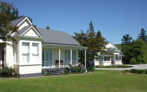 White villa-style buildings with verandas set on a lawn with trees