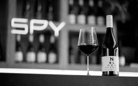 Wine glass and bottle on cellar door counter in black and white