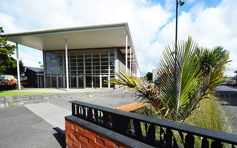 Mid-century community centre exterior with flat canopy roof and floor-to-ceiling glazing