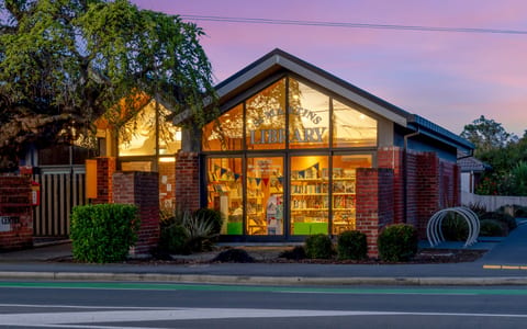 Brick community centre library building lit up at dusk