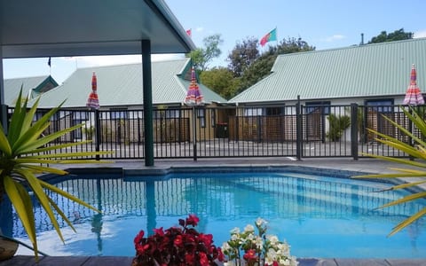 Outdoor pool area with umbrellas and low-set buildings behind