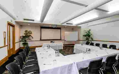 Conference room with U-shaped table, projection screen and plants