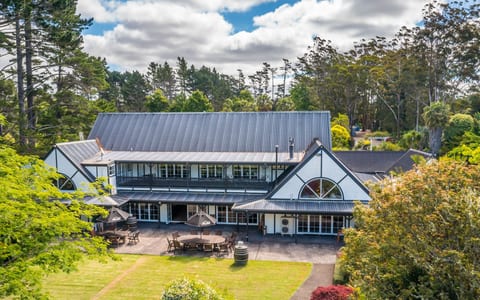 Lodge building with steeply pitched roof set among trees with outdoor dining area
