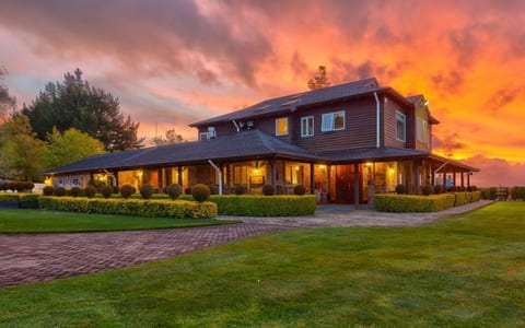 Timber homestead exterior at sunset with manicured lawn and topiary hedges