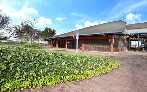 Single-storey library building with timber roof and hedge-lined frontage